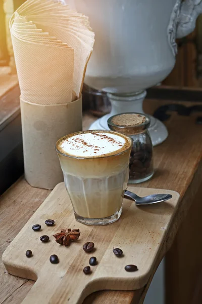 Xícara de café de cappuccino e grãos de café na mesa de madeira .effect borrão estilo vintage e ruído — Fotografia de Stock