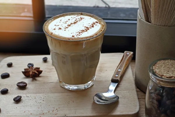 Чашка кофе капучино и кофейных зерен на деревянном столе. — стоковое фото