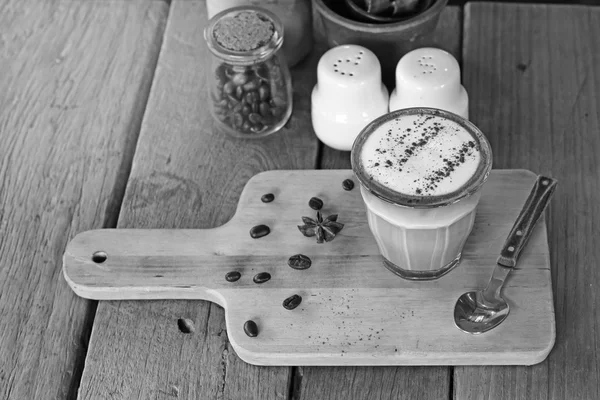 Cangkir kopi cappuccino dan biji kopi di atas meja kayu — Stok Foto