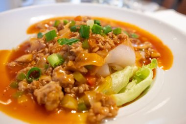 Üzerine tatlı ve ekşi dilimler, kıymalı domuz eti, tonlarca marul ve marulla süslenmiş erişte..