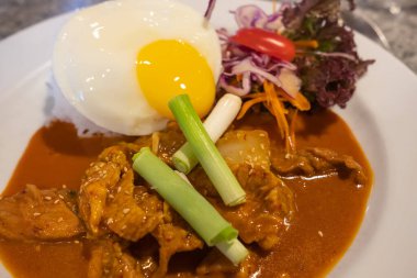 Domuz göbekli pilav, kızarmış yumurtayla servis edilen kimchi ve soğanlı süsleme..