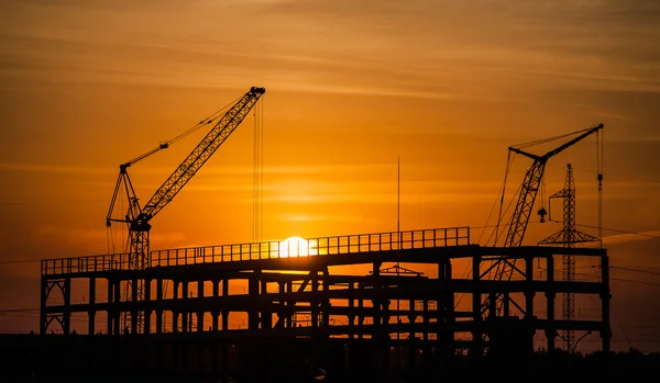 Vinçler ve binalar batan güneşe karşı yapım aşamasında