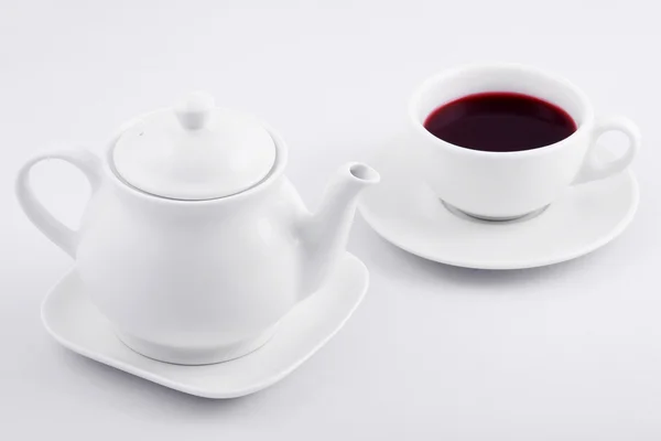 white tea cup with red tea and white teapot on white background