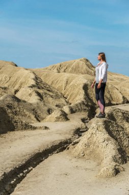 Açık havada egzersiz yapan ve spor giyimli genç bir kız, Romanya 'daki çamur volkanları parkında çekilmiş bir fotoğraf.