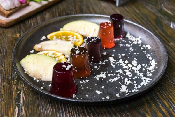 Different kinds of sweet jelly shots with alcohol with slices of apple and orange