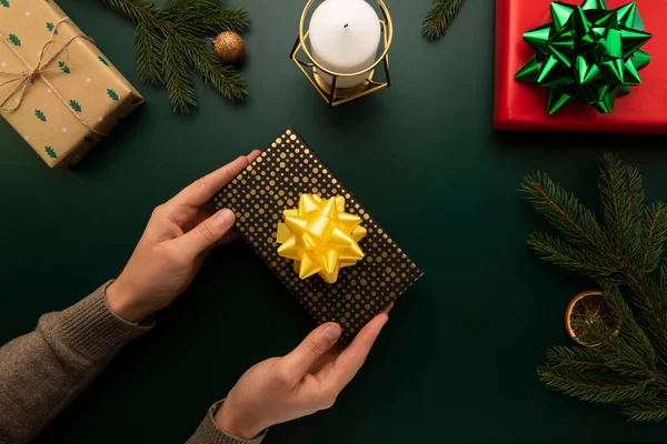 Bir adam elinde Noel hediyesi olan bir kutu tutar..