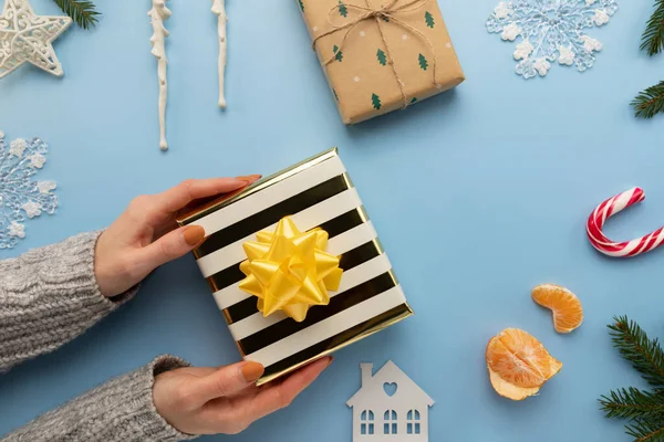 Bir kadın güzel paketlenmiş bir Noel hediyesi tutuyor..