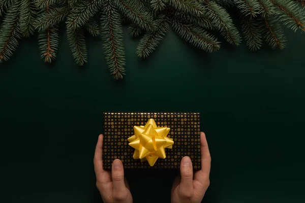 Adamın elinde güzel paketlenmiş bir Noel hediyesi var.