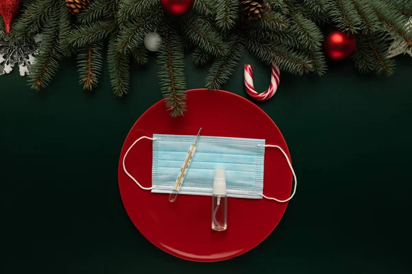Masada Noel süsüsüyle süslenmiş tıbbi maskeli bir tabak var. Salgının Noel kutlaması üzerindeki etkisinin kavramsal fotoğrafı.