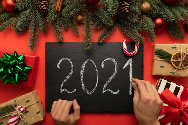 Bir adam siyah granit tablete tebeşirle 2021 yazısını yazar..