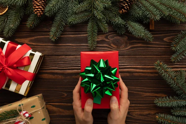 Adamın elinde güzel paketlenmiş bir Noel hediyesi var.