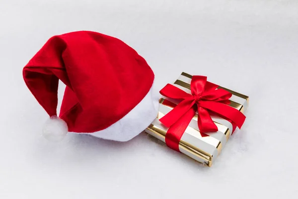 Noel hediyesi ve Noel Baba şapkası karların üzerinde duruyor. Hediye değiş tokuş etme geleneği.