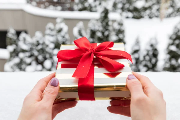 Kadın eli bir Noel hediyesi tutuyor. Hediye değişimi geleneği.