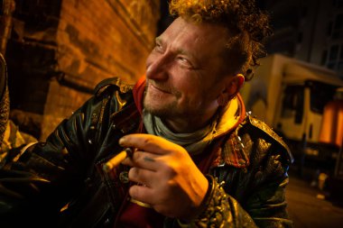 Berlin 'de geceleri sokakta sigara içen ve gülümseyen evsiz bir adam..