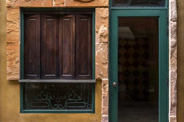 Janela de madeira e porta de vidro verde na parede amarela — Fotografia de Stock