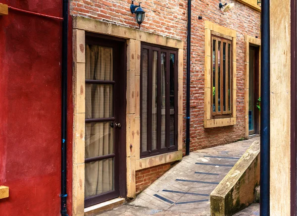Beco vazio com janelas e portas na parede de tijolo — Fotografia de Stock