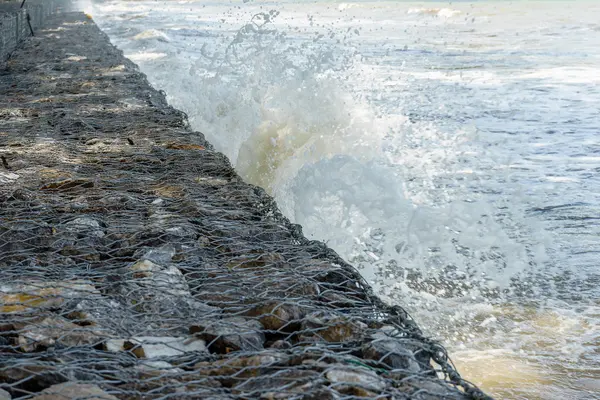 Vågorna krascha in långa stone seawall — Stockfoto