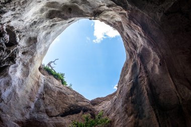 Mavi gökyüzü ile kayalık mağarada büyük delik
