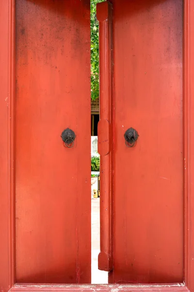 Старі червоні дерев'яні двері з металевою ручкою кільця — стокове фото