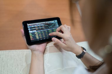 Borsa kontrol etmek için tablet kullanan kadın
