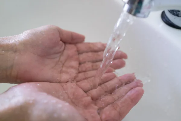 Mani di una donna che si lava sotto il rubinetto — Foto Stock