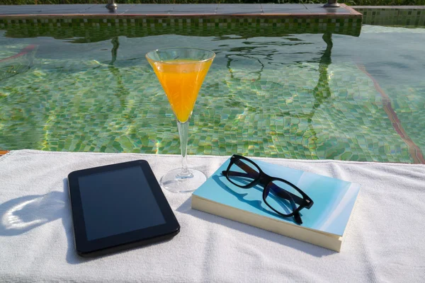 Tablet ile boş perde, bir bardak portakal suyu ve mavi kitap beyaz havlu gözlüklerle