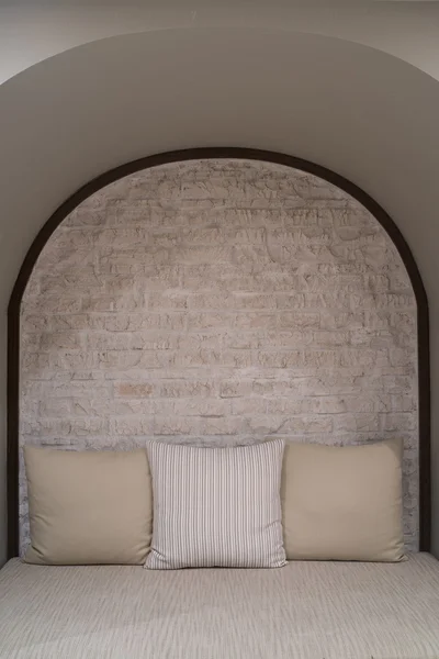 Sofá de pano com travesseiros castanhos e parede de tijolo — Fotografia de Stock