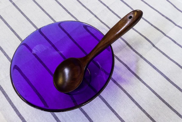 Cuchara de madera en tazón de cristal de cocina púrpura claro colocada en blanco — Foto de Stock