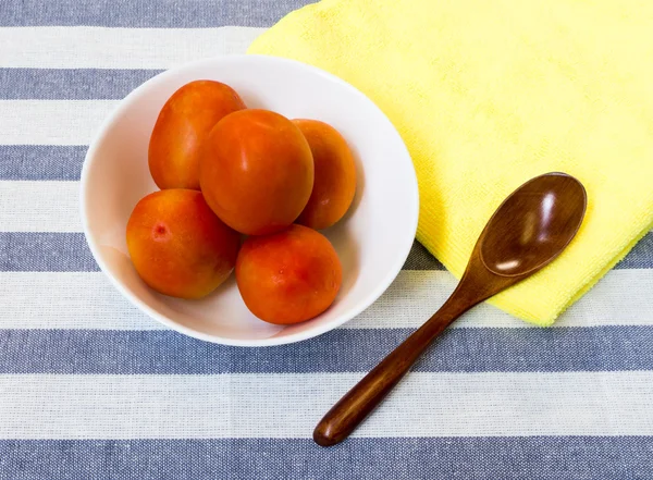 Wooden Spoon with White Bowl with Five Tomatoes Placed on Yellow Stok Foto Bebas Royalti