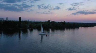 Dnipro nehrinde gece yüzen bir yat. Karanlık nehir ufkunda güneş batıyor. Gün batımında yelken açmak