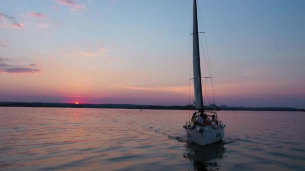 Weiße Jacht segelt auf Antenne für den Sonnenuntergang. Rosafarbener Himmel, traumhafter Sonnenuntergang und im Fluss Dnipro schwimmendes Segelboot — Stockvideo