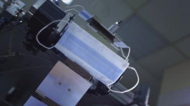 Virüse karşı korunmak için tek kullanımlık tıbbi maske üretimi. Tıbbi giysi üretimi için fabrikanın atölyesinde tıbbi banttaki maske. Yüz maskesi üretimi.