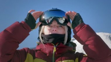 Güzel bir kız kış gözlüğü takar ya da snowboard yaparken maske takar. Sporda zafer kavramı, kazanmak, kazanmak. Karlı bir yamaçta kayak yapmaya hazırlanıyorum. Kayak merkezinde kış seyahati