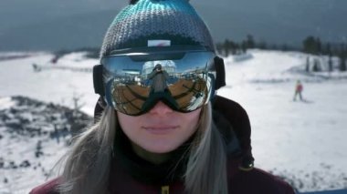 Güzel bir kız kış gözlüğü takar ya da snowboard yaparken maske takar. Sporda zafer kavramı, kazanmak, kazanmak. Karlı bir yamaçta kayak yapmaya hazırlanıyorum. Kayak merkezinde kış seyahati