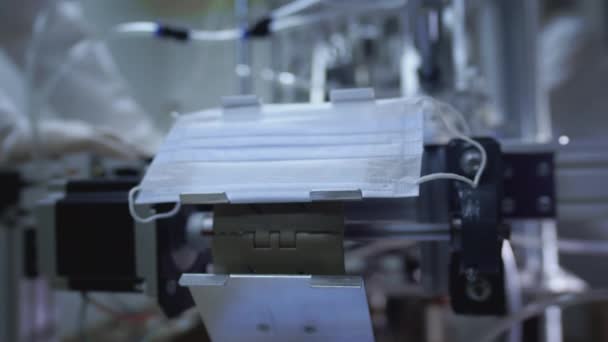 Productie van medische maskers. Het masker valt van een machine of transportband in een kartonnen doos. Creëren van medisch materiaal tijdens een pandemie of quarantaine. Beschermende maskers tegen het coronavirus. — Stockvideo