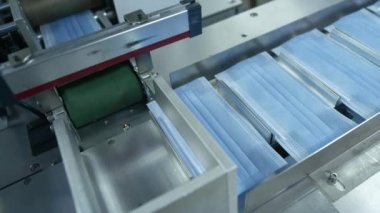 Tıbbi üç katmanlı mavi ya da beyaz maske üretimi. Yeni maskeler taşıma bandında hareket ediyor. Hastalarla ilgilenen doktorların yüz maskeleri. Koronavirüs salgını sırasında koruyucu maskeler yapıyorlar..