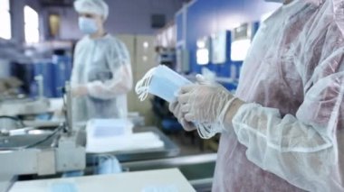 Koruyucu tıbbi maskeler üreten bir fabrikadan bir grup işçi. Yüz maskeleri plastik torbalara konur. Coronavirüs veya covid-19 'a karşı koruyucu ekipman üretmek için makine