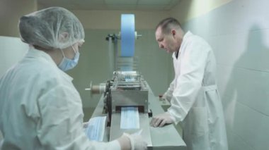 Tıbbi koruyucu yüz maskeleri üretimi. Coronavirus koruma makinesi, covid-19. Beyaz önlüklü bir mühendis tıbbi maskeler üretme sürecini kontrol ediyor.