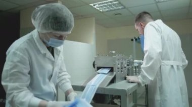 Tıbbi koruyucu yüz maskeleri üretimi. Coronavirus koruma makinesi, covid-19. Beyaz önlüklü bir mühendis tıbbi maskeler üretme sürecini kontrol ediyor.