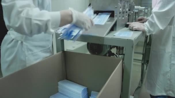 의료용 마스크의 제작. 코로나 바이러스 보호 장치 , covid-19. 흰색 외투를 입고 일하는 기술자가 의료용 마스크를 만드는 공정을 제어 한다 — 비디오