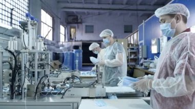 Koruyucu tıbbi maskeler üreten bir fabrikadan bir grup işçi. Yüz maskeleri plastik torbalara konur. Coronavirüs veya covid-19 'a karşı koruyucu ekipman üretmek için makine