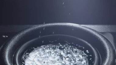 Siyah bas woofer. Sudan hoparlör. Su damlacıkları bas sesiyle patlar. Hoparlörden sıvı sıçraması. Parti ya da konser için arka plan. Yavaş çekim.