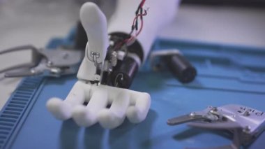 Masanın üzerinde kol protezi var. Parçalanmış robot kol protezi bir mühendislik masasında.