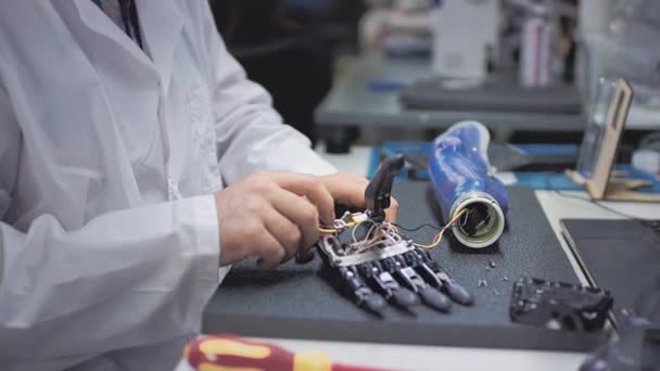Παραγωγή ενός προσθετικού χεριού. Ένας επιστήμονας μηχανικός δημιουργεί ή διαγνώνει ένα ρομποτικό προσθετικό βραχίονα. Προσθετικό εργαστήριο. Ένα μηχανικό χέρι για μια γεμάτη ζωή. Δημιουργία κυβερνητικών άκρων — Αρχείο Βίντεο