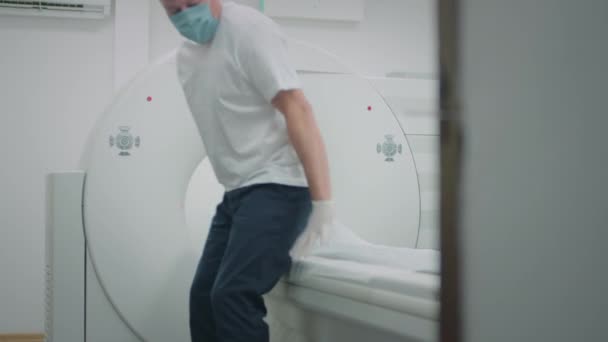 El médico hace una resonancia magnética para un paciente en una clínica. El macho yace en el dispositivo de resonancia magnética. Tecnologías modernas en medicina. Examina los pulmones. Tomografía computarizada durante una pandemia de coronavirus o covidio — Vídeo de stock