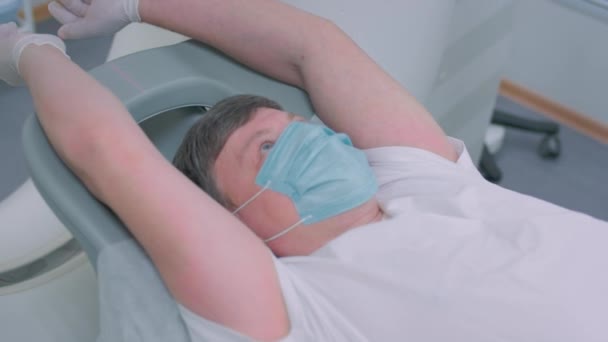 医生在诊所为病人做核磁共振扫描.男性躺在核磁共振装置中。医学的现代技术。检查肺。大肠病毒大流行期间的计算机断层扫描 — 图库视频影像
