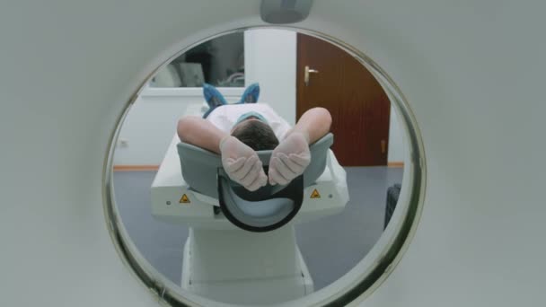 Een patiënt met een medisch masker ligt aan een moderne computer tomografie machine. De dokter analyseert de longen op een CT-scanner. Het gevaar van covid of coronavirus. Onderzoek van het orgaan van de longen. — Stockvideo