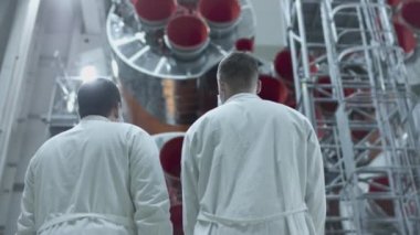 İki mühendis uzay gemisini inceliyor, tablete yazıyor. Askeri bir hangarda fırlatılmaya hazır bir uzay roketi. Uzay teknolojileri. Big Rocket 'in inşaatı. Uzayda İnsanlık.