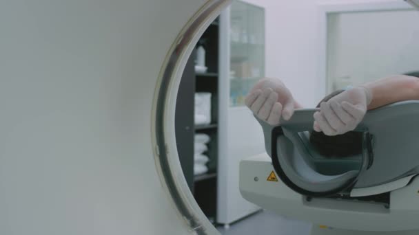 Um paciente em uma máscara médica protetora encontra-se em um aparelho computadorizado moderno da tomografia. O médico analisa os pulmões num tomógrafo. O perigo de covid ou coronavírus. Exames pulmonares humanos. — Vídeo de Stock