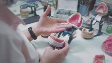 Yetişkin kadın sıhhiyeci laboratuarda takma diş yapıyor. Diş protezi tutan bir cerrah. Dişçilikte gelişmiş teknoloji. Diş implantı ve yapay diş üretimi. Kırmızı EPIC.